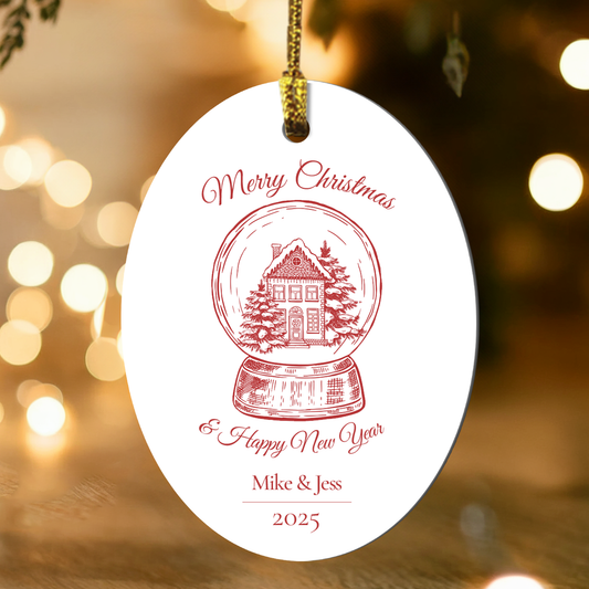 Decorative Christmas ornament with a house design and text, hanging against a festive background with lights.