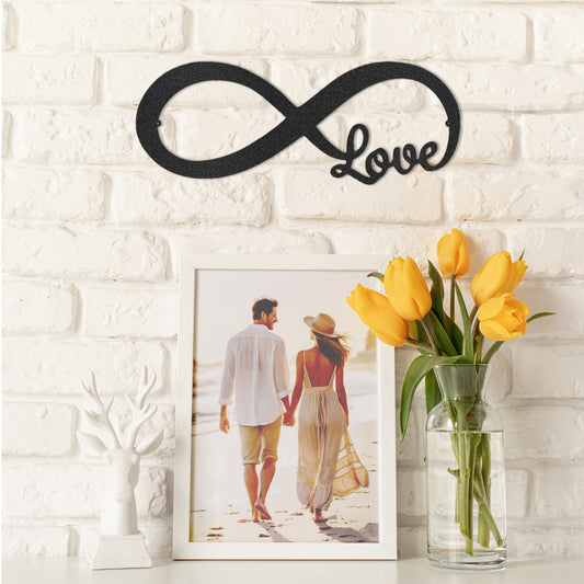 Decorative wall art with infinity symbol and 'Love' text, framed photo, and vase of yellow tulips on a white brick wall.