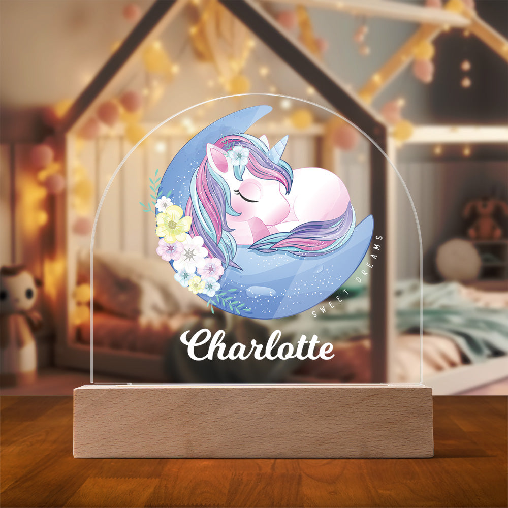 Dome shaped acrylic plaque featuring a unicorn curled up asleep on a crescent moon with the words 'Sweet Dreams' and a child's name in a bold script font.