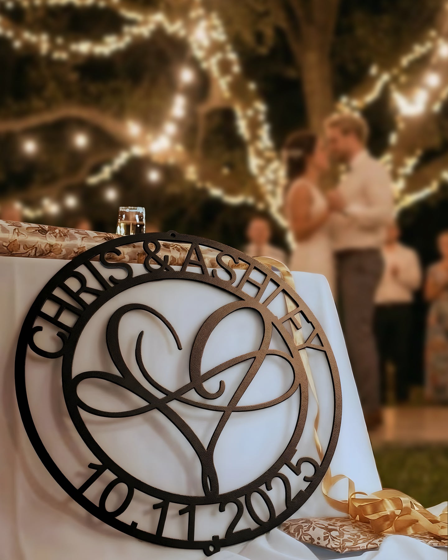 Infinite Love Personalized Metal Decor piece gently resting against a table with a romantic night time country wedding scene blurred in the background.