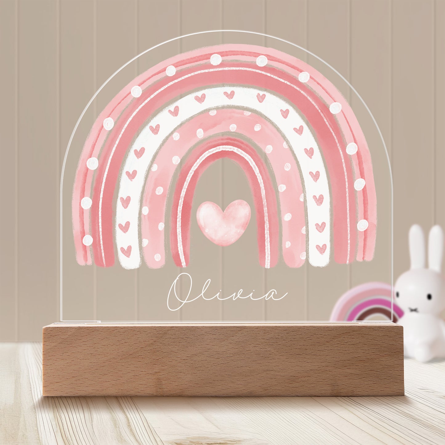 Boho Rainbow Personalized Night Light with Battery powered base featured on a light timber table with a neutral beige panelled wall and bunny and rainbow ornaments in the background.