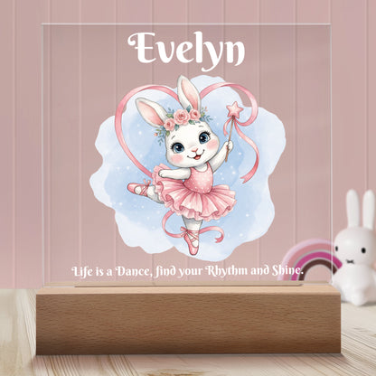 Ballerina Bunny Personalized Night Light with Battery powered base featured on a light timber table with a pastel pink panelled wall and bunny and rainbow ornaments in the background.
