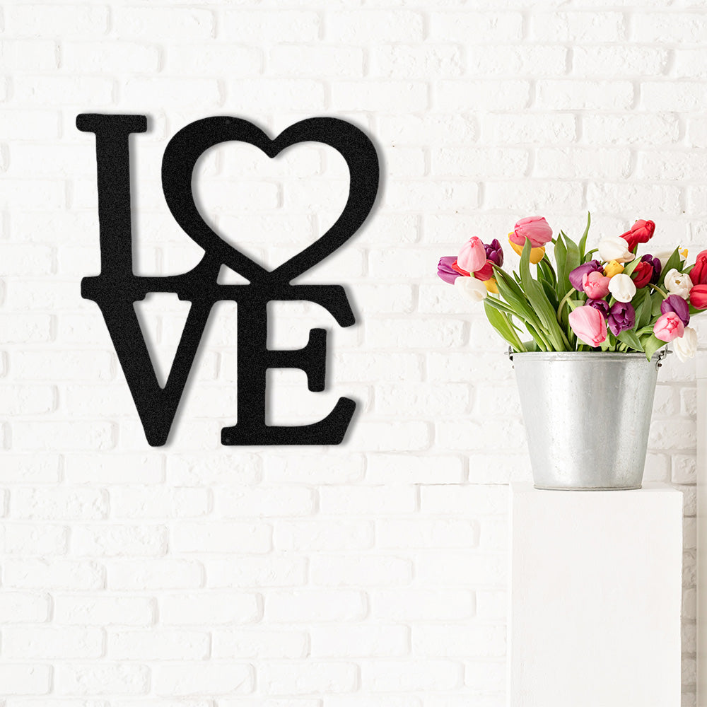 Classic Love Metal Decor displayed in Black on a modern white brick wall next to a bucket full of colorful tulips.